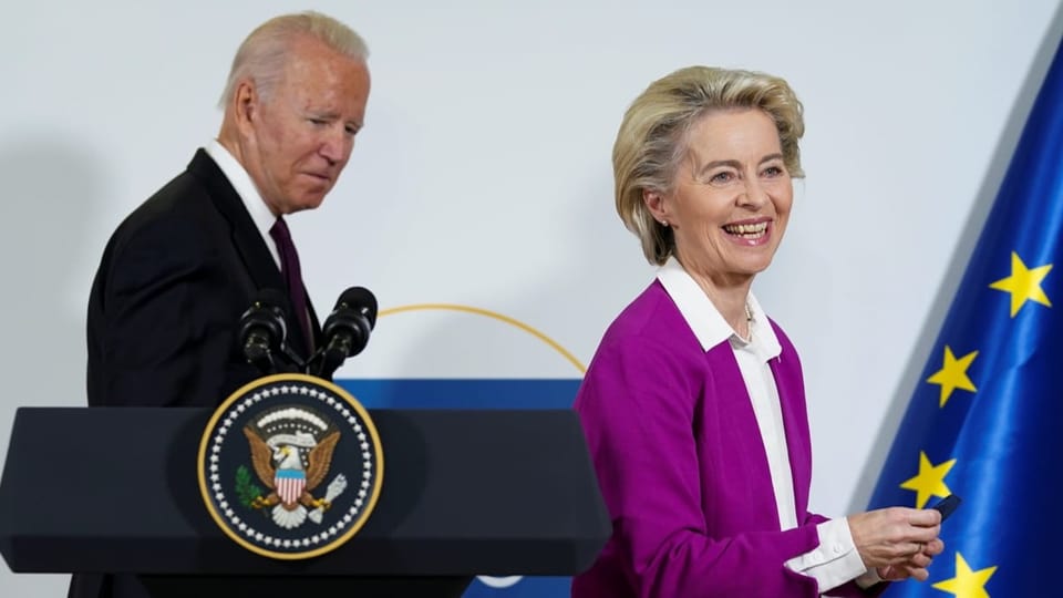 Joe Biden und Ursula von der Leyen lächeln neben einer EU-Flagge