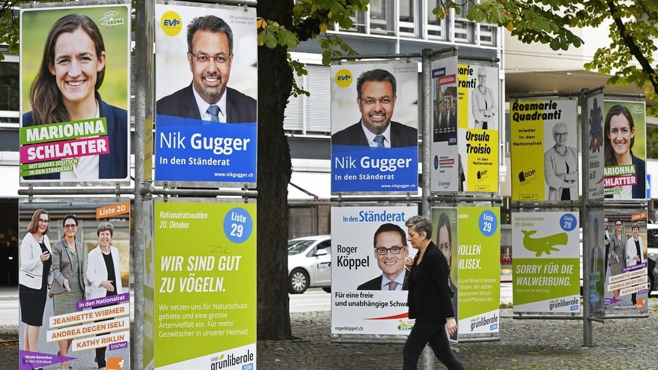Eine Frau läuft in Zürich an Plakaten für die eidgenössischen Wahlen 2019 vorbei.