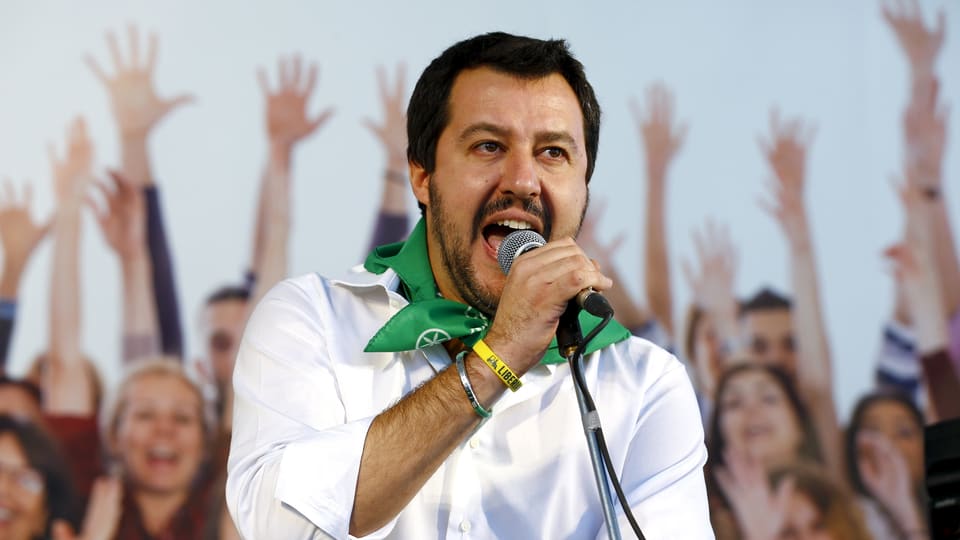 Salvini spricht in ein Mikrofon, im Hintergrund Anhänger, welche ihre Arme in die Luft strecken.