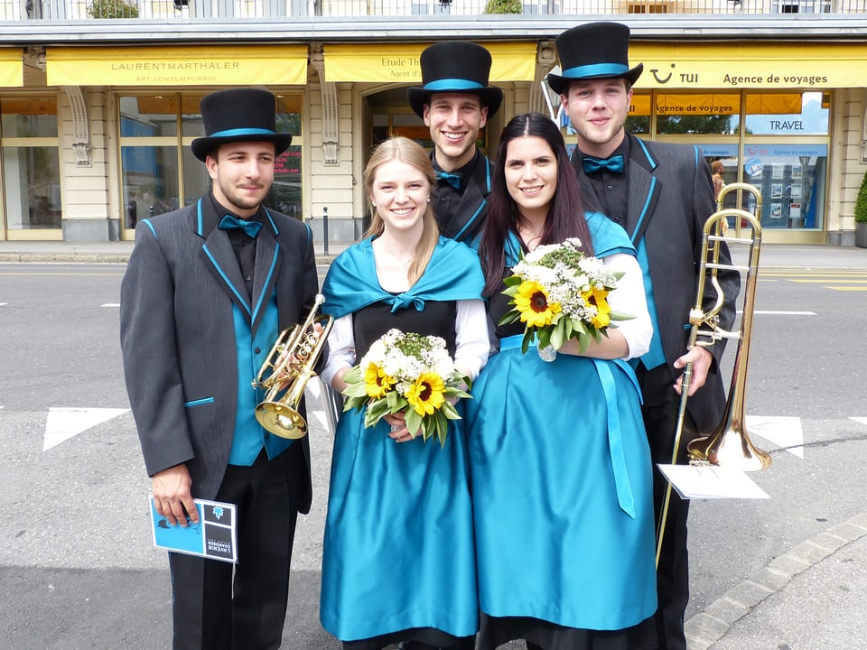 Drei Männer und zwei Frauen in schwarz-blauen Uniformen. Die Männer tragen Zylinder.