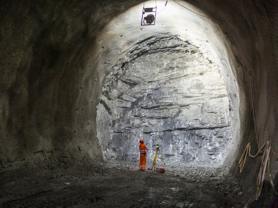 Mann in Schutzkleidung vor einer Felswand im Tunnel stehend