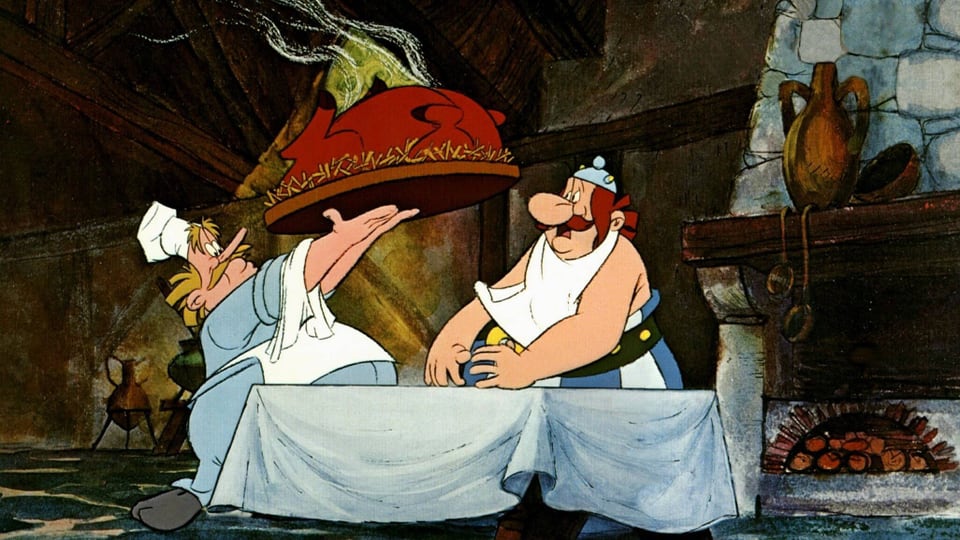 Ein Koch stellt Obelix einen grossen Braten auf den Tisch.