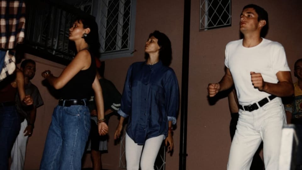 Älteres Farbfoto von drei tanzenden Mensch, links junge Frau in hohen Jeans, Mitte Frau in Bluse, rechts Mann in weiss.