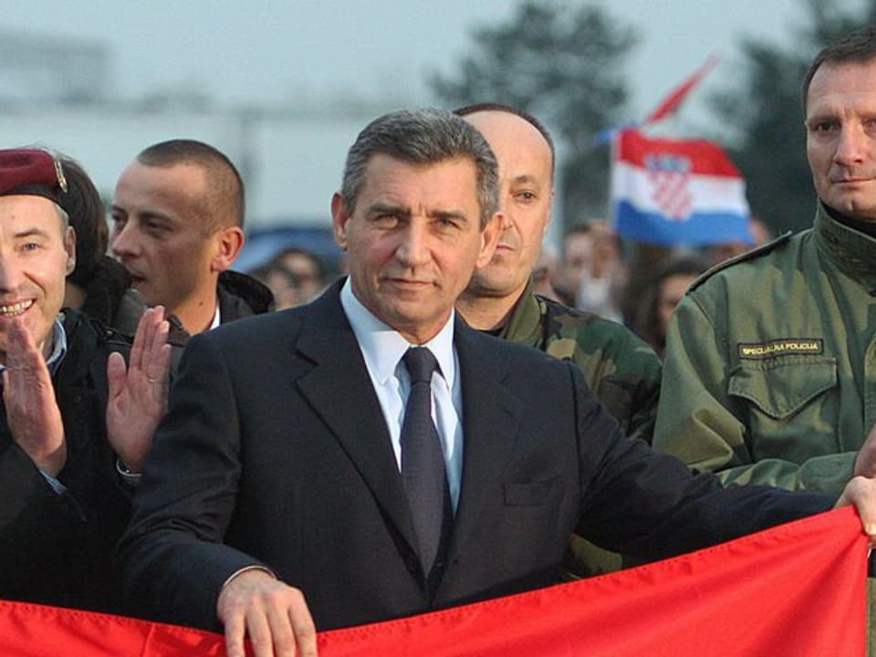 Ante Gotovina steht inmitten einer Gruppe und hält eine kroatische Fahne.