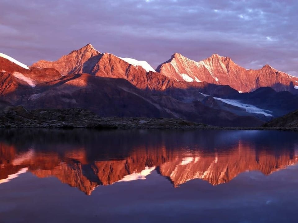 Bergkette spiegelt sich in einem Bergsee bei Sonnenaufgang. 