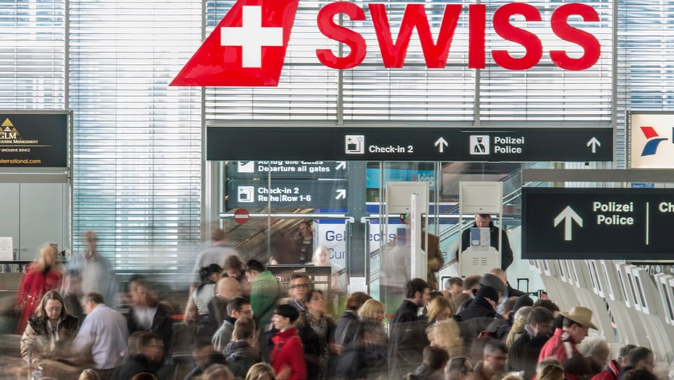 Swiss-Logo am Flughafen Kloten mit Passagieren.