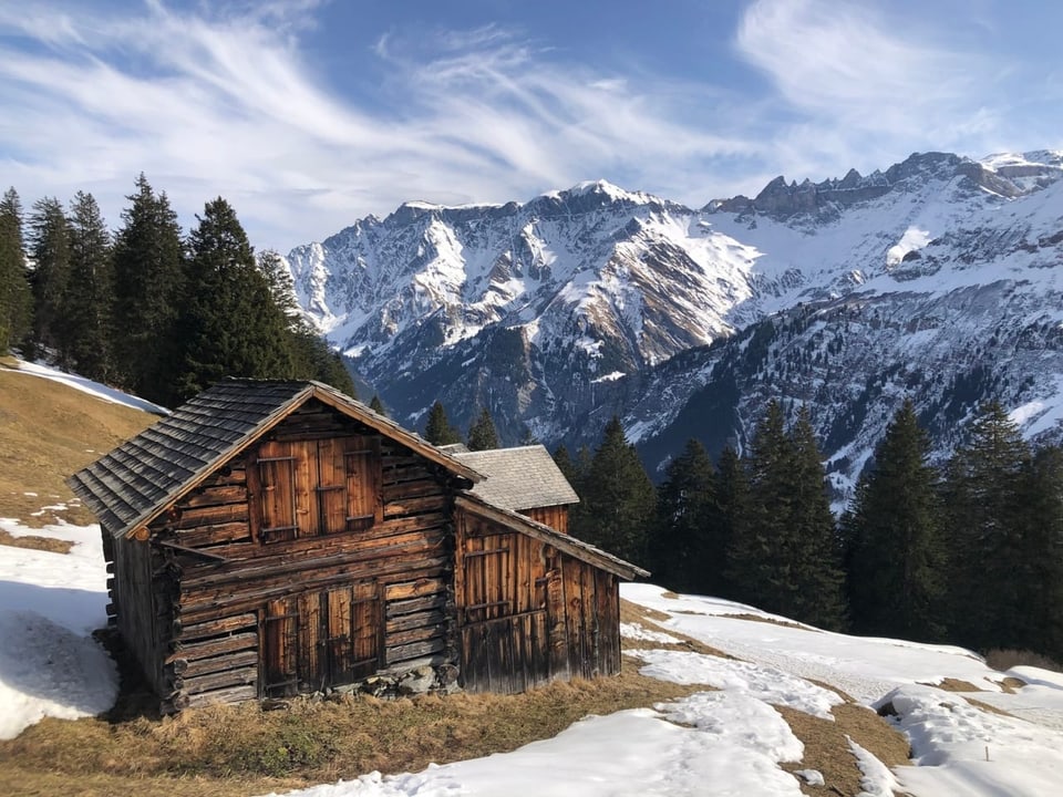 Alphütte mit Schneeresten und aperen Stellen.