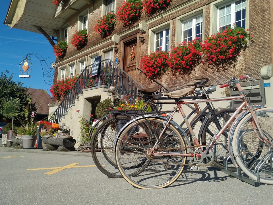 Gasthof mit Geranien, im Vordergrund alte Fahrräder