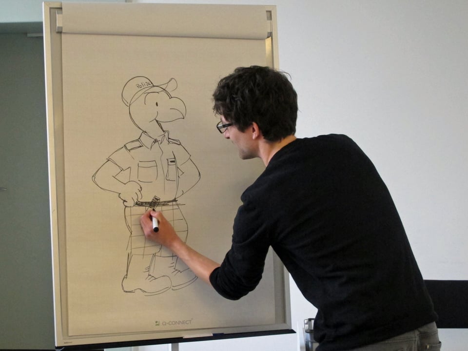 Zeichner Samuel Glättli demonstriert auf einem Flipchart, wie er den Globi in Polizeiuniform malt.