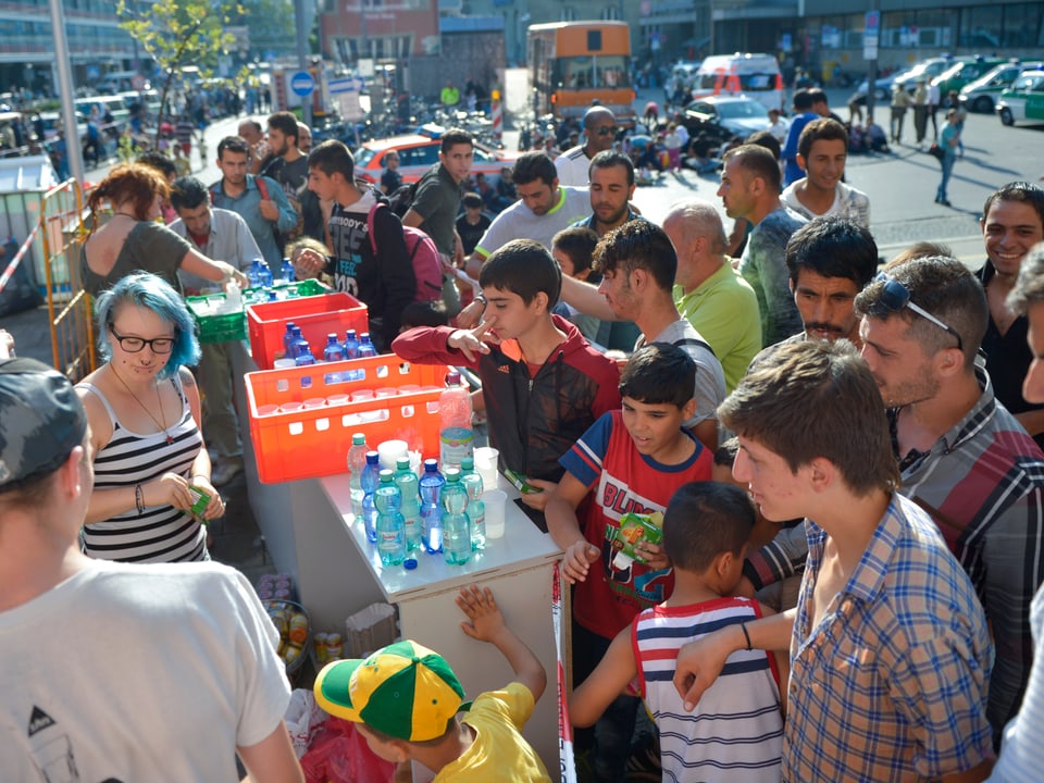 Helfer verteilen Wasser an Flüchtlinge. 