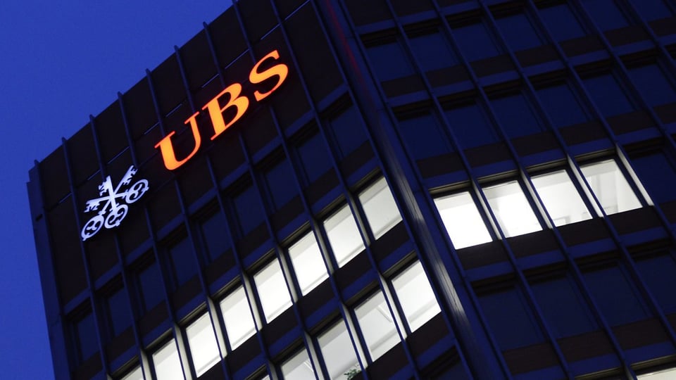 Leuchtendes UBS-Logo an einem Gebäude.