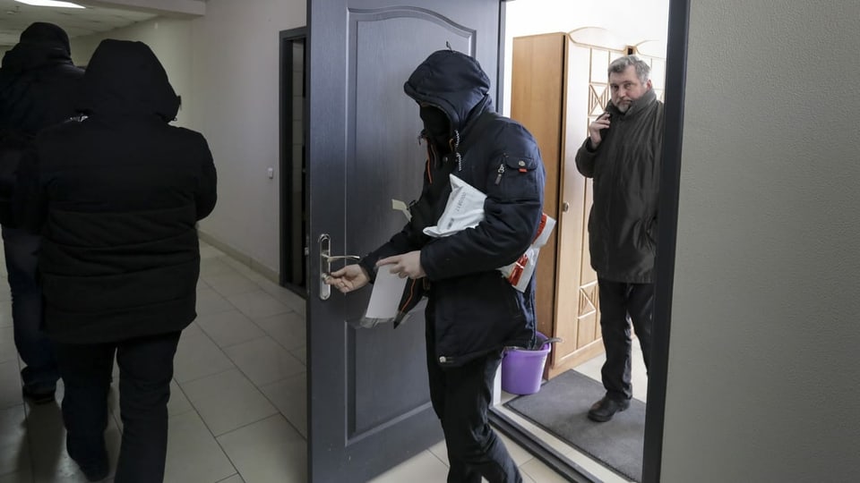 Polizisten tragen Dokumente und Computer aus dem Büro des weissrussischen Journalistenverbandes, während Andrei Bastunets, der Leiter des Verbandes, rechts, im Büro in Minsk, Belarus, steht, Dienstag, 16. Februar 2021