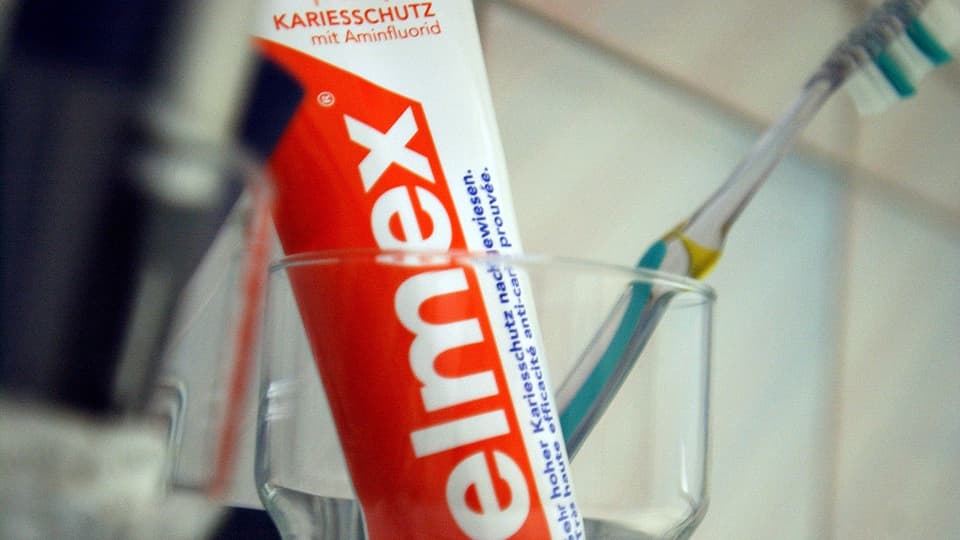 Elmex-Zahnpasta in einem Glas.