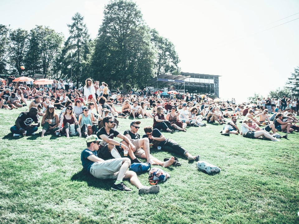 Festival-Besucher sitzen auf dem Boden. 