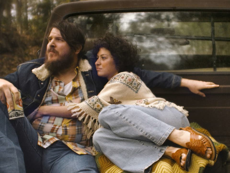 Filmszene: Ein Mann und eine Frau sitzen auf der Ladefläche eines Pickups.