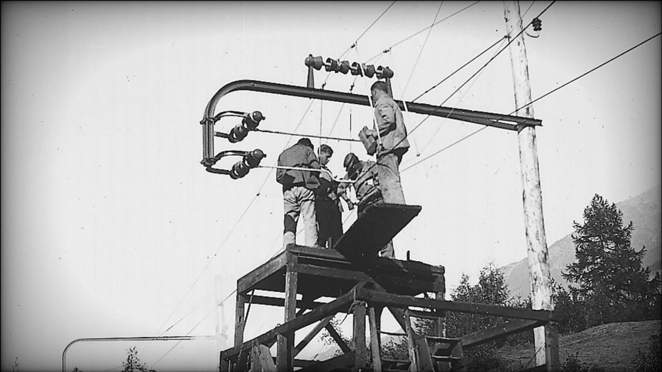 Vier Männer auf einer Archivaufnahme, die eine Leitung der Berninabahn montieren.