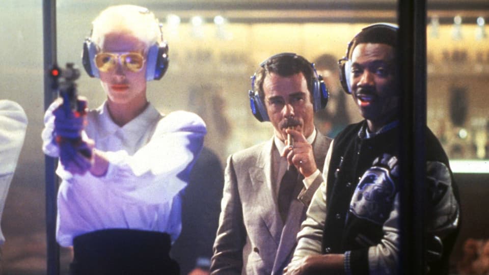 Film-Still aus «Beverly Hills Cop II»: Murphy steht mit Brigitte Nielsen und Dean Stockwell am Schiessstand.