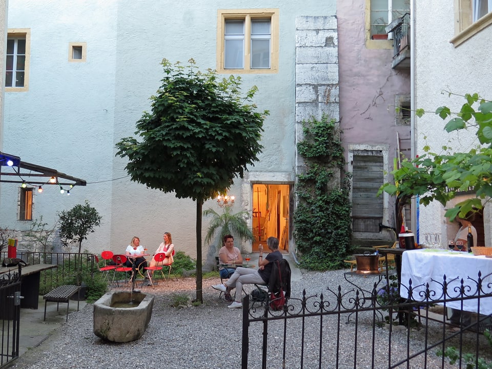 Innenhof mit kleinem Baum und Brunnen, wenige Stühle