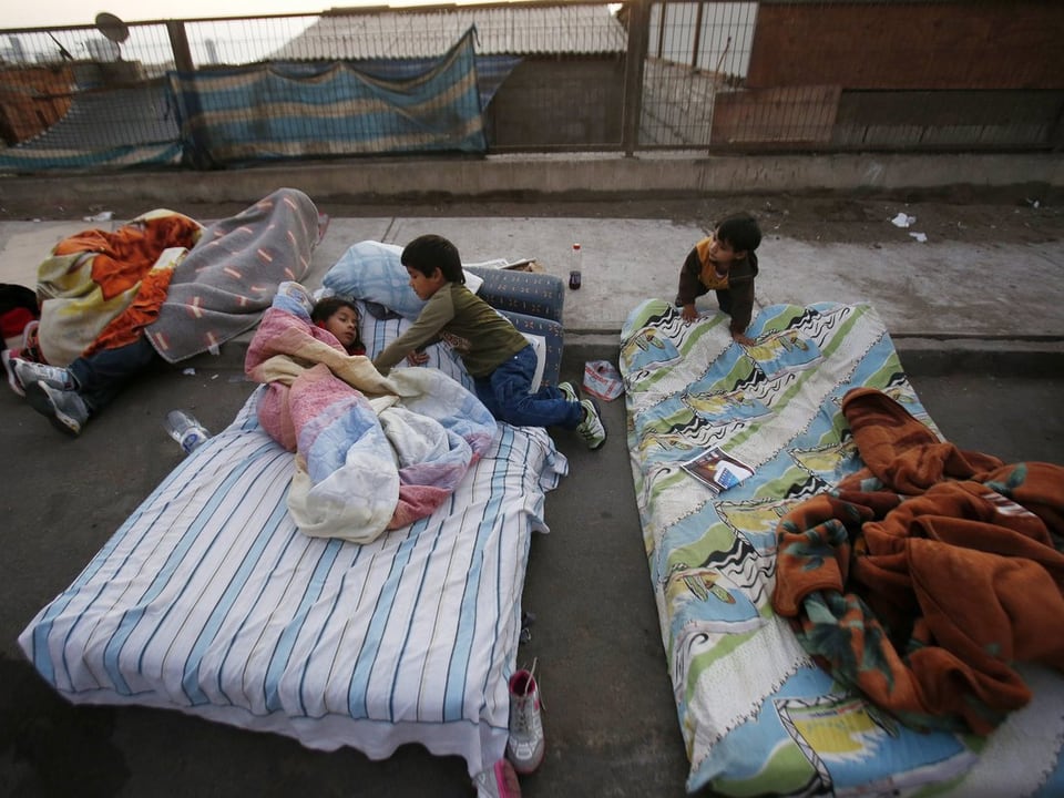 Kinder auf Matratzen, die auf der Strasse liegen.