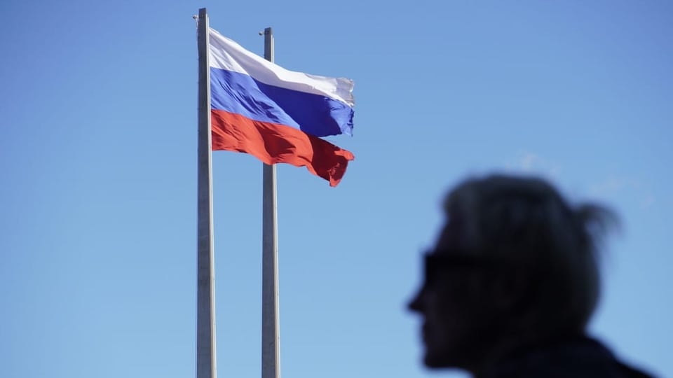 Russische Flagge, davor eine Silhouette einer Person.