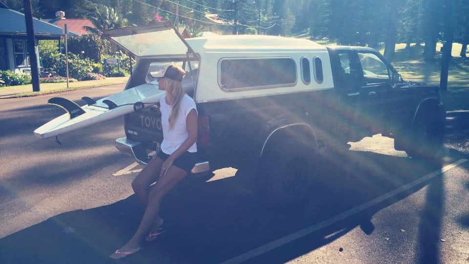Christa posiert mit Surfboard und Jeep und sieht cool aus wie eine hawaiianisches Surfergirl