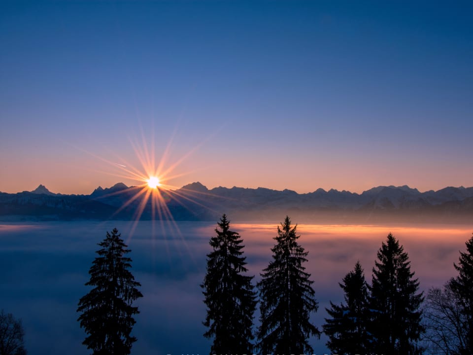 Sonnenaufgang über den Bergen, darunter das Nebelmeer.