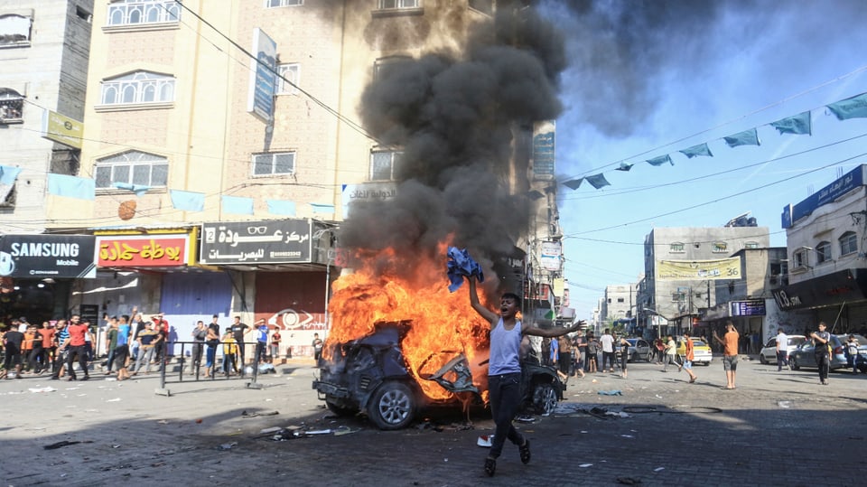 Ein Junge steht neben einem israelischen Militärfahrzeug, das in Flammen steht.