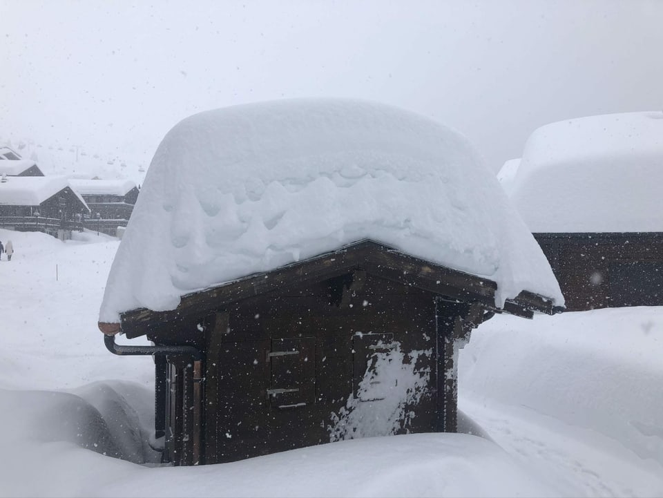 Tiefverschneite Winterlandschaft. Im Vordergrund Stall mit mindestens 1 Meter Schnee auf Dach.
