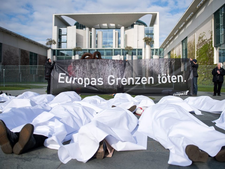 Demonstranten liegen vor dem Bundeskanzleramt mit einem Transparent «Europas Grenzen töten» auf dem Boden.