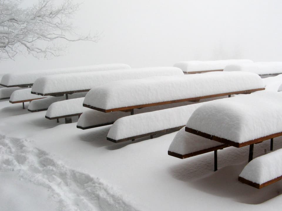 Die Gartentische und -bänke eines Gasthauses sind mit viel Schnee beladen.