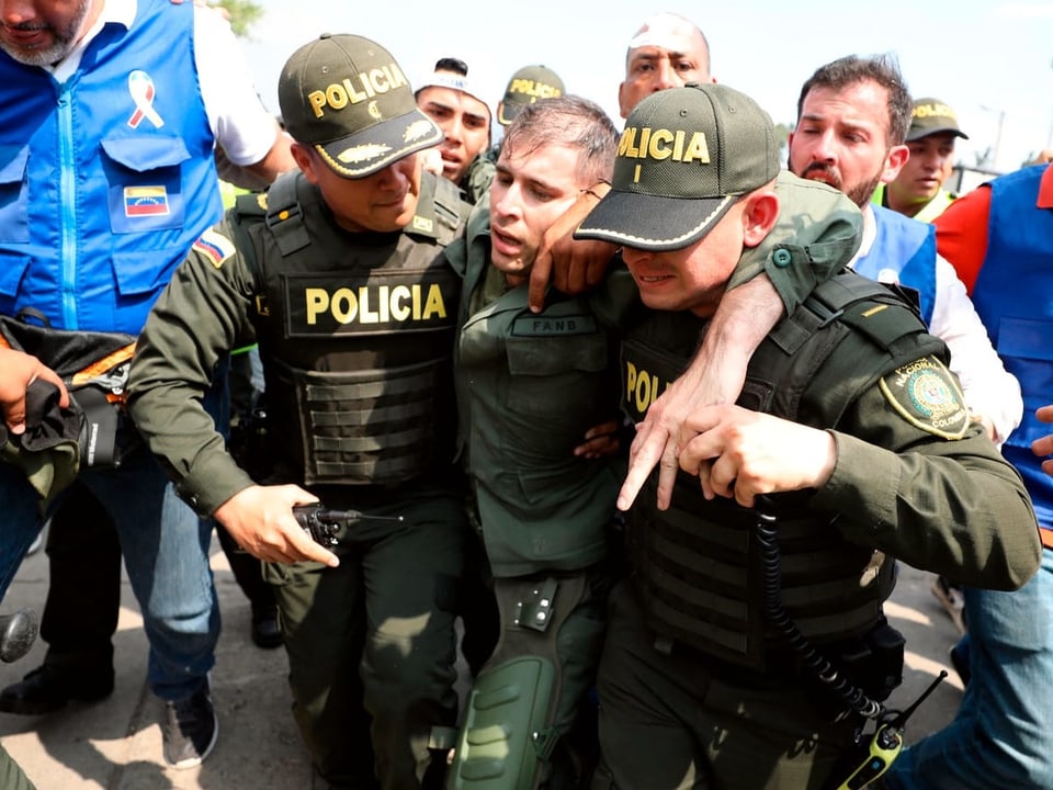 zwei kolumbianische Polizisten stützen einen Soldaten.