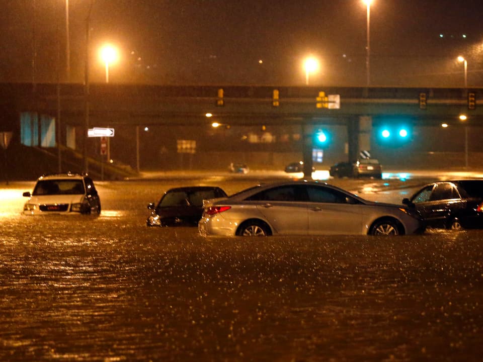 Autos in einer überfluteten Strasse. 
