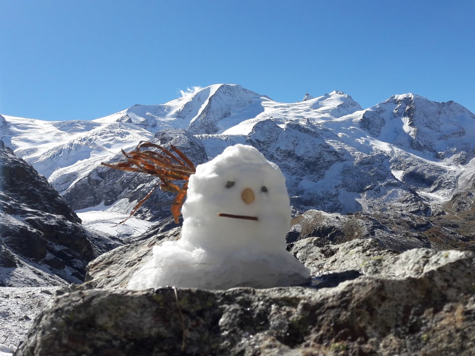 Ein kleiner Schneemann mit Bergpanorama.