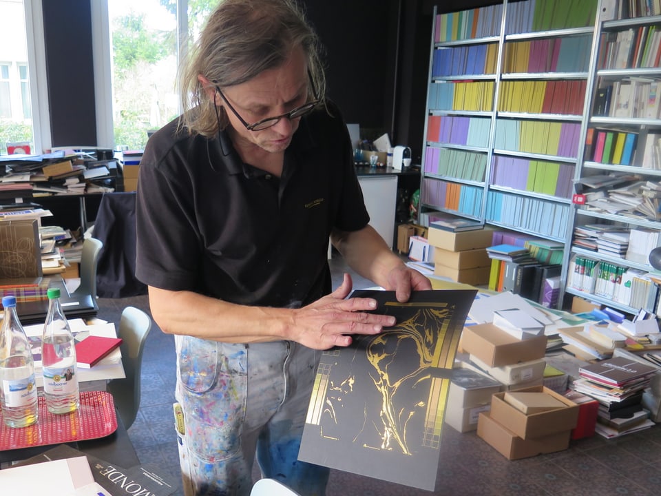 Lorenz Boegli in seinem Atelier mit einem Golddruck auf schwarzem Papier.