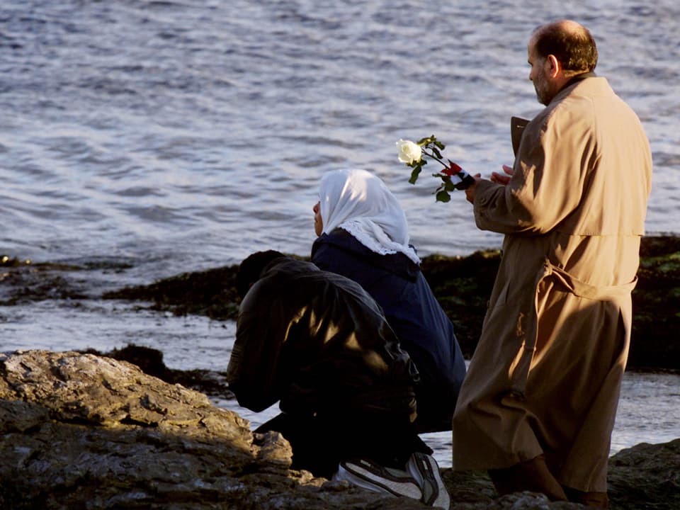 Angehörige der Absturz-Opfer von Flug 990 d stehen betend mit Blumen am Meer in Newport, Rhode Island.