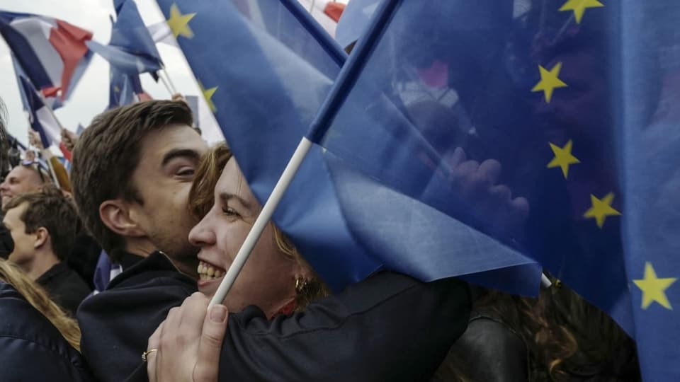 Zwei Franzosen liegen sich mit Flaggen in den Armen.