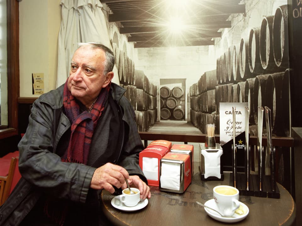 Autor Rafael Chirbes sitzt an einem Tisch und rührt in seinem Kaffee.