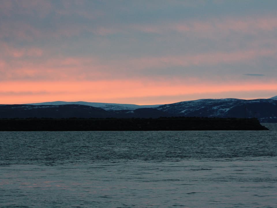 Blick von Honningsvag nach Süden, wo der Himmel in zartes Rot gehüllt ist.