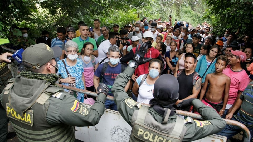 Das kolumbianische Militär hält Menschen zurück, die hinter einer Absperrung darauf warten, endlich nach Venezuela zurückkehren zu können.