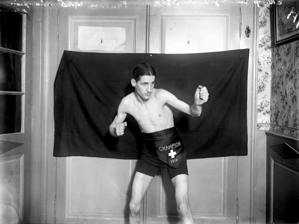 Mann in Boxerpose vor einem Vorhang in Boxerhosen.