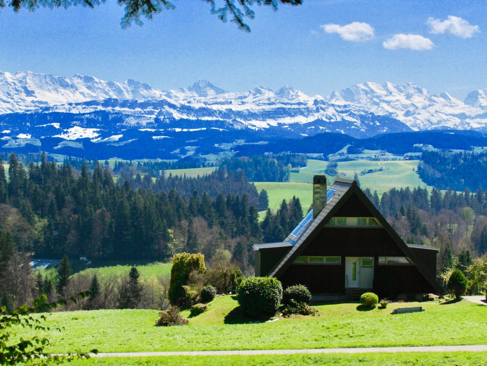 Haus, im Hintergrund die Alpen. 