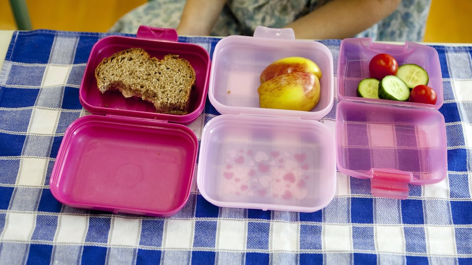 Drei geöffnete Znüni-Boxen mit Apfel, Gemüse und Brot.