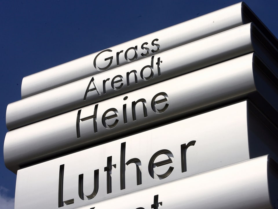 Auf einer Skulptur sieht stilisierte Bücher, auf denen «Luther» oder «Heine» stehen