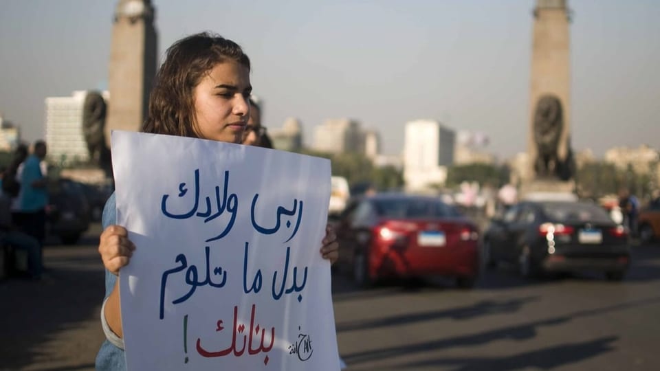 Mädchen hält ein Transparent mit der Aufschrift «Diszipliniere deine Jungs, anstatt deine Mädchen zu beschuldigen».
