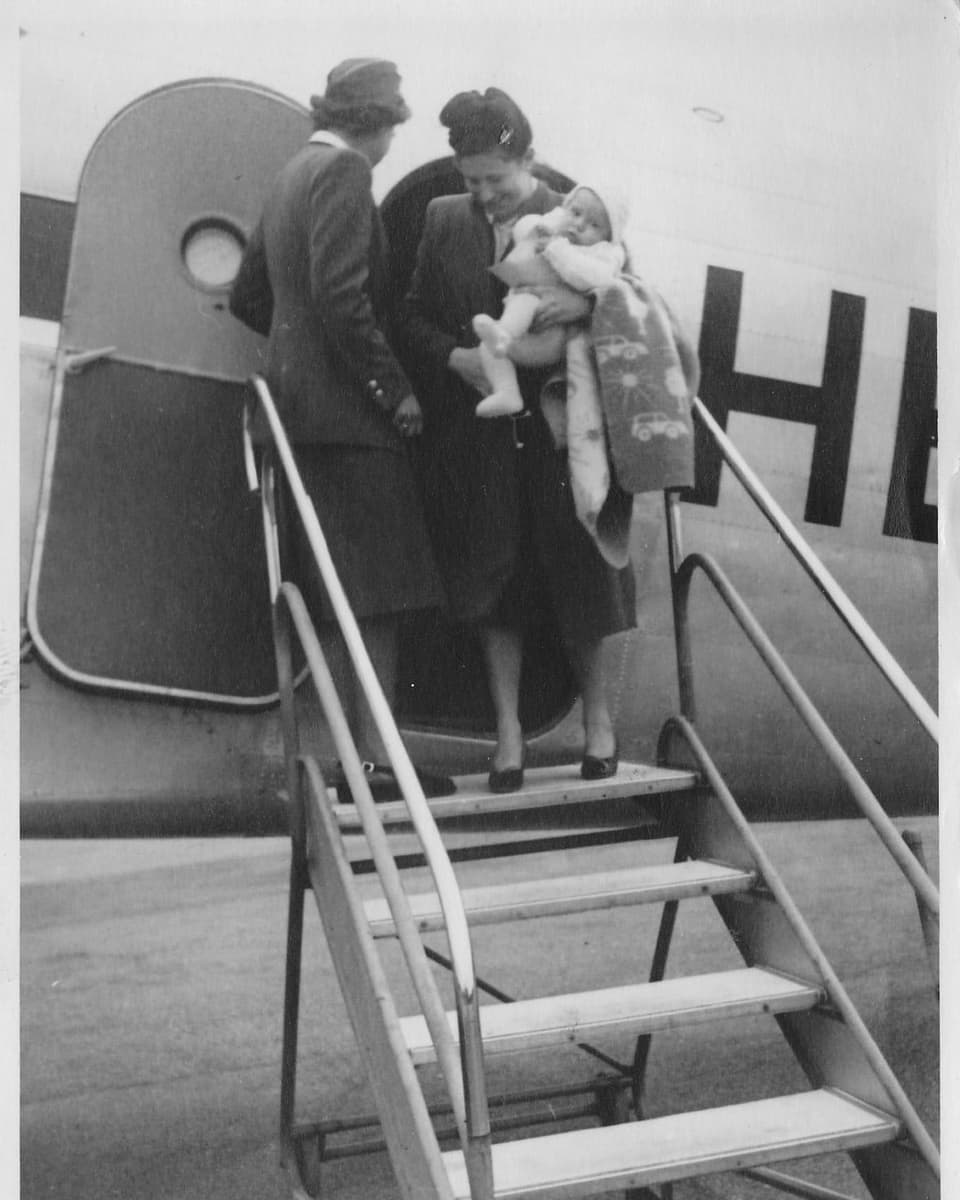 Frau mit Baby vor Flugzeug