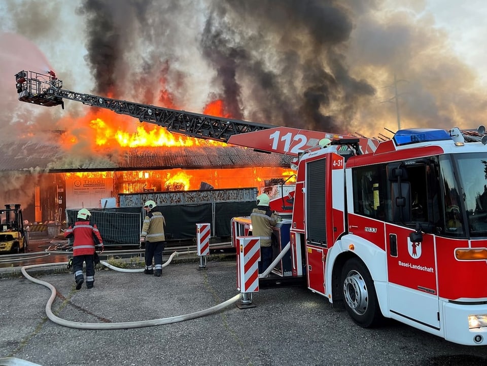 Feuerwehrwagen neben brennender Lagerhalle