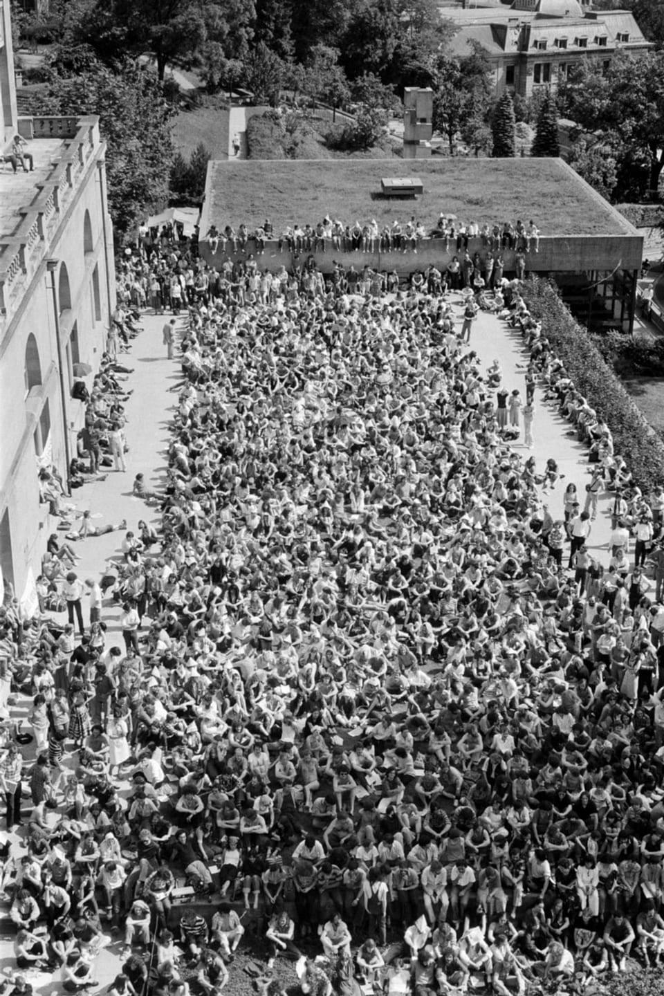 Luftaufnahme einer grossen Menschenmenge bei einer Versammlung im Freien.