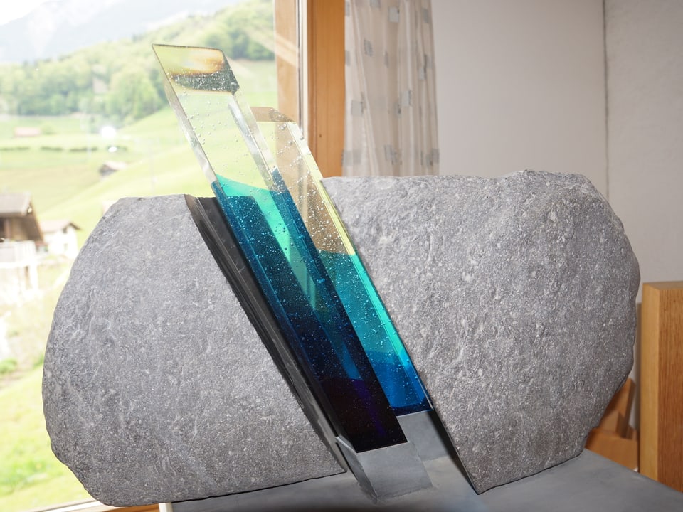 Bunte Glasscheiben ziehen sich mitten durch einen grauen Stein.