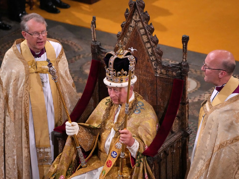 König Charles III. sitzt nach der Krönung mit der Edwardskrone auf dem Thron.