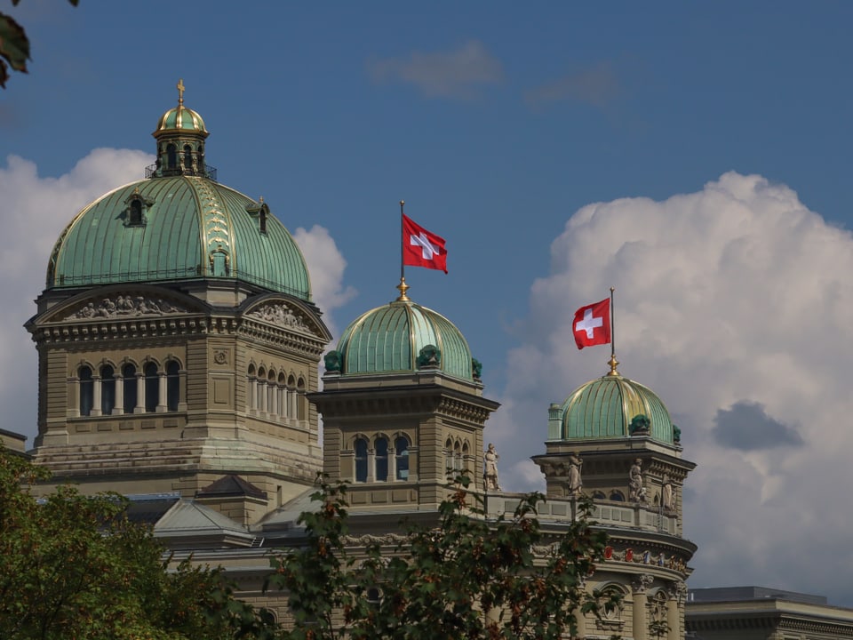 Winden aus verschiedenen Richtungen bewgen die Schweizerflaggen auf dem Bundenshaus.